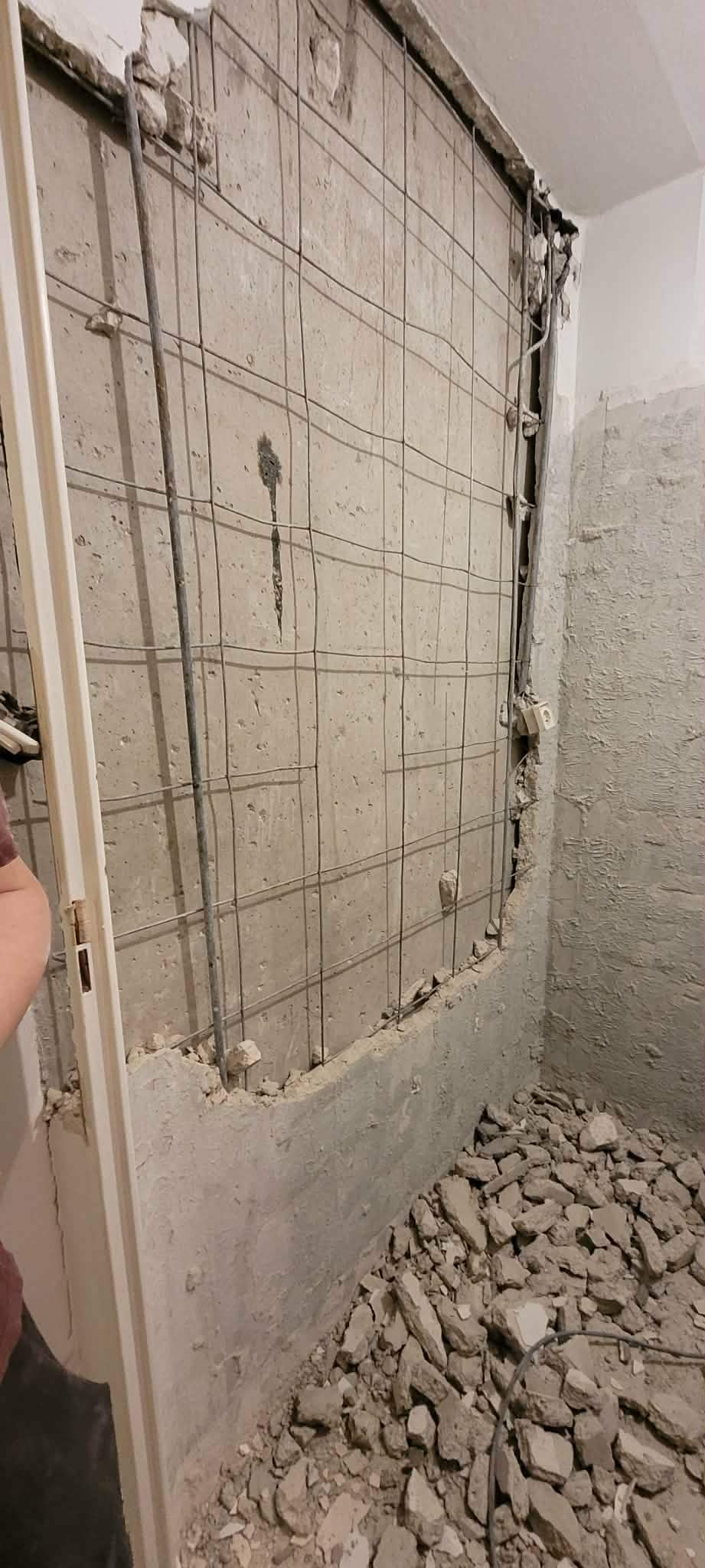 Wyburzanie ściany z żelbetu między łazienką a WC, widoczne zbrojenie, realizacja Ursynów